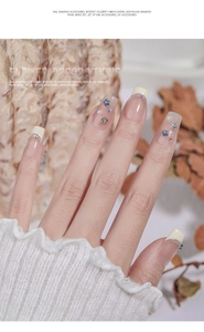 Detailed view of French manicure featuring mini metal flowers and 3D mixed diamond pearls