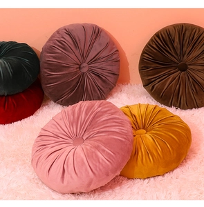 Detail of round pleated velvet pumpkin pillows in various warm colors on a soft rug