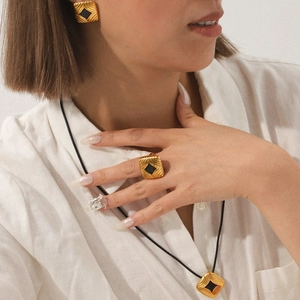 Detail of 18K gold stainless steel jewelry set with black enamel squares and textures