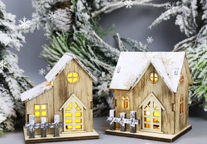 Primo piano di accoglienti casette di Natale in legno a LED con tetto innevato e recinto