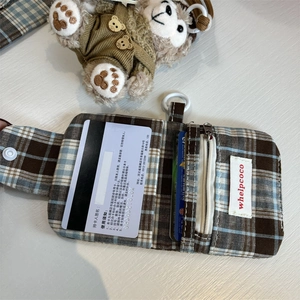 Detail view of plaid card holder with card slots, zipper, and hanging loop for storage