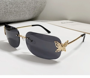 Detail von randloser Sonnenbrille mit goldenen Schmetterlings-Deko und Strasssteinen