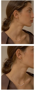 Close-up of golden pear-shaped drop earrings and double-layered pearl necklace on a model