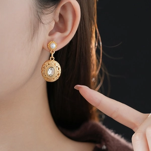 Close-up of vintage baroque pearl earrings with golden hollow drop and zircon on a model
