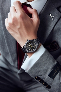 Close-up of luxury black stainless steel men's watch with day-date display and gold indices