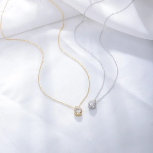 Elegant gold and silver pear-cut zircon teardrop necklaces on white silk fabric