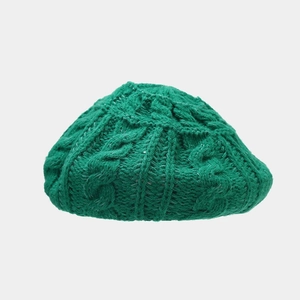 Macro detail of emerald green cable knit beret showing thick wool texture and ribbing