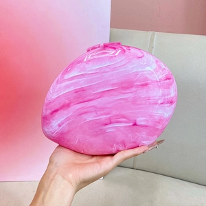Close-up of pink marble acrylic clutch bag with artistic stone texture in hand