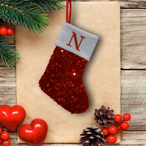 Detail of red sequined Christmas stocking with embroidered letter N on a festive background