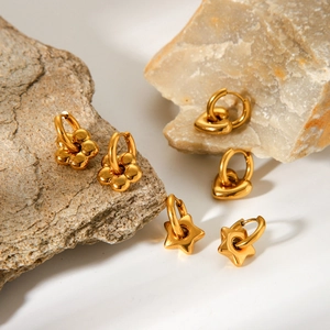 Close-up of golden stainless steel hoop earrings with heart, flower, and star charms