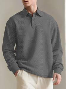 Detail shot of the dark grey polo shirt showing its unique jacquard texture and buttons