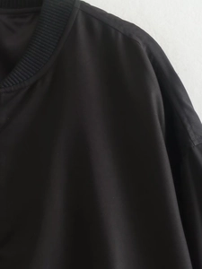 Macro view of the ribbed neckline and shoulder texture on a black bomber jacket