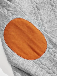 Close-up of jacquard knit texture and orange elbow patch on the grey henley shirt