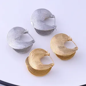 Detailed view of textured gold and silver crescent C-shape earrings with ribbed finish