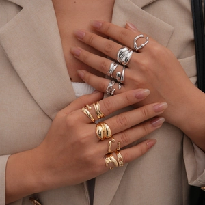 Dettaglio di anelli geometrici minimalisti in oro e argento indossati su una mano