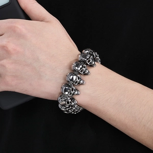 Punk style skull head link bracelet in silver-grey metal for men on black background
