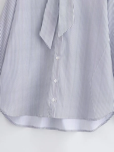 Close-up of blue and white striped poplin shirt featuring lace-up collar and button details