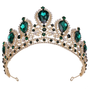 Macro detail of gold bridal tiara with pear-shaped emeralds and sparkling rhinestones