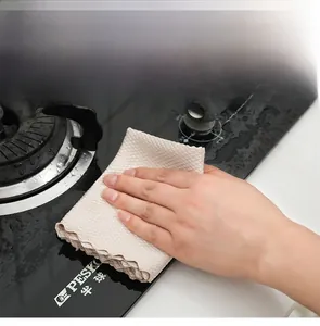 Gros plan d'un chiffon microfibre à écailles beige nettoyant une plaque de cuisson