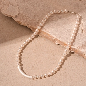 Detail of minimalist pearl necklace showing the matte silver tube and lobster clasp
