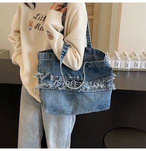 Détail du sac cabas en denim bleu avec broderie 7 STREET LANE et effet effiloché