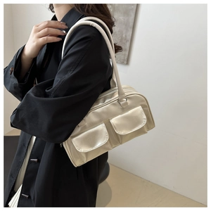 Detail of champagne gold shoulder bag with dual front pockets and sleek strap