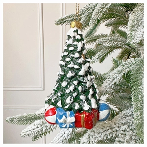 Christmas tree ornament with white snow and gift boxes hanging on a snowy branch
