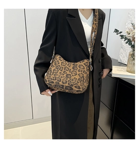 Model wearing leopard print shoulder bag with matching wide strap over a black blazer