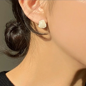 Close-up of a minimalist 925 silver earring with cream resin inlay worn on ear