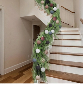 Green Christmas garland with multi-colored balls wrapped around a stair railing