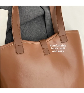 Detail of brown faux leather tote bag showing flat shoulder strap and matte texture