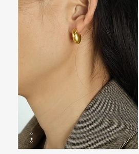 Detailed macro view of small 18K gold plated hoop earring worn on a model earlobe