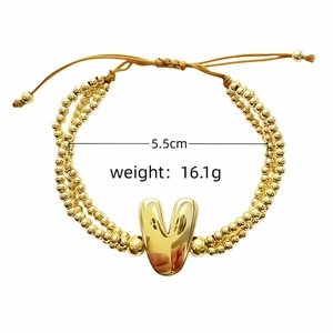 Détail d'un bracelet triple rang en perles dorées avec pendentif lettre V