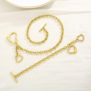Flat lay of gold heart necklace and bracelet set with T-bar toggles on textured fabric