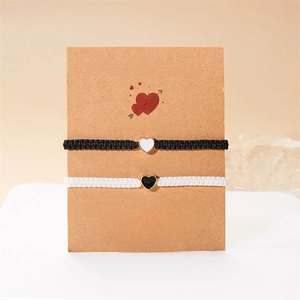 Dettaglio di braccialetti fatti a mano per coppia su carta regalo con cuoricini