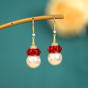 Detail of luxury long tassel earrings with red roses and white pearls on a gold stand