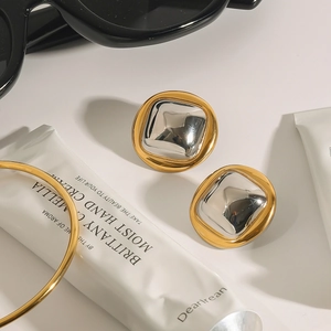 Close-up of two-tone metal earrings in gold and silver finish on a minimalist background