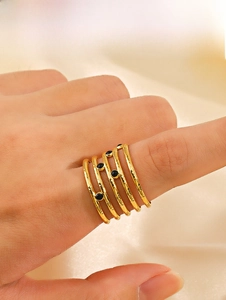 Detail of five-layer gold wavy ring with black beads on beige silk fabric