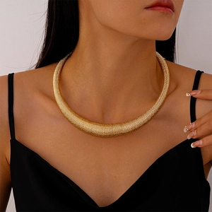 Detail of chunky gold spiral texture choker necklace on model with edgy metallic style
