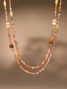 Detailed close-up of colorful zircon beads and shell tiger eye stones on a steel necklace