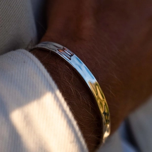 Macro view of wide silver polished stainless steel cuff bracelet with hammered texture