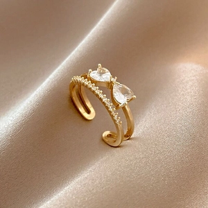 Double-layered gold ring with heart zirconia stones on champagne silk fabric
