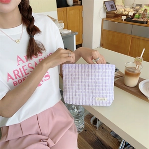 Detailed view of purple checkered makeup bag being opened in a cozy cafe setting