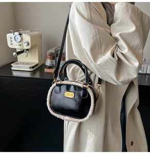 Close-up of black PU leather pillow bag with white faux fur trim and gold hardware