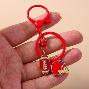 Red metal football and helmet keychain held against a warm beige background