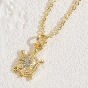 Macro detail of golden sea turtle pendant featuring sparkling zircon stone inlay