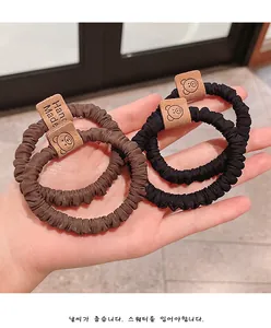 Detailed view of elastic scrunchies featuring a handmade bear leather tag and pleated fabric