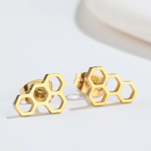 Close-up detail of golden hollow hexagon honeycomb earrings with a polished metal finish
