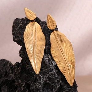 Macro shot of 18K gold plated leaf earrings with brushed texture on black rock