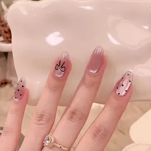 Detail of pink cat eye nails with black polka dots and hand-painted bow design